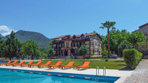 a pool with orange chairs in front of a building at Enso Inn in Fethiye