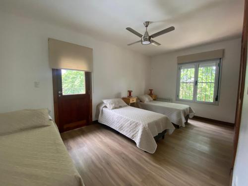 a bedroom with three beds and a ceiling fan at Al puente y palo in San Lorenzo