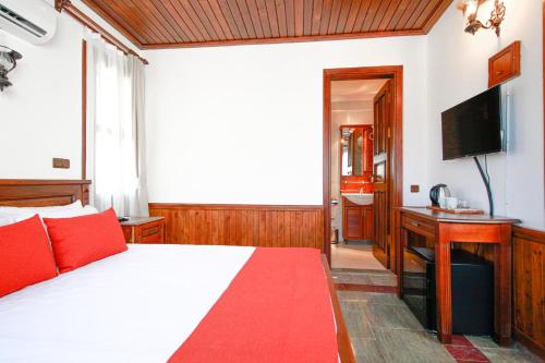 a bedroom with a bed with red pillows and a television at Enso Inn in Fethiye