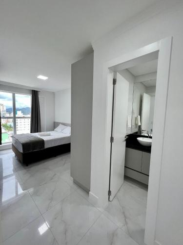 1 dormitorio con cama, lavabo y espejo en Apartamento próximo à praia, en Itapema