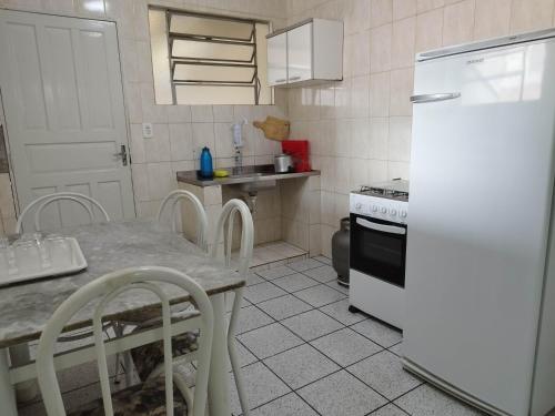 une cuisine avec une table et un réfrigérateur blanc dans l'établissement Seu Apto na Praia da Costa 9 Simples e Barato Mobiliado Ar Cond Fogão TV Geladeira Local Excelente no Centro, à Vila Velha