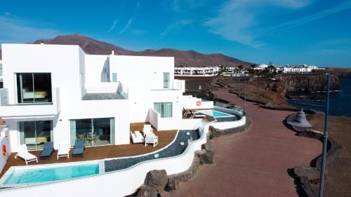 CalaLanzarote Suites Hotel - Adults Only في بلايا بلانكا: مبنى ابيض كبير به مسبح