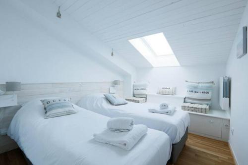 two beds in a white room with towels on them at Sur l'îlot de St Martin au centre du port vue exceptionnelle ! in Saint-Martin-de-Ré