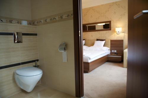 ein Bad mit einem Bett und einem WC in einem Zimmer in der Unterkunft Airport Wellness Panzio in Hajdúszoboszló
