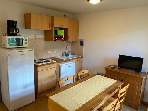 une cuisine avec une table et un réfrigérateur blanc dans l'établissement residence clos la Chalp II, à Molines-en-Queyras