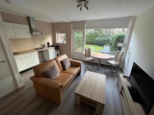 ein Wohnzimmer mit einem Sofa und einem Tisch in der Unterkunft Bosvakantie Veluwe - Huisje 54, Hoefbos, Otterlo in Otterlo