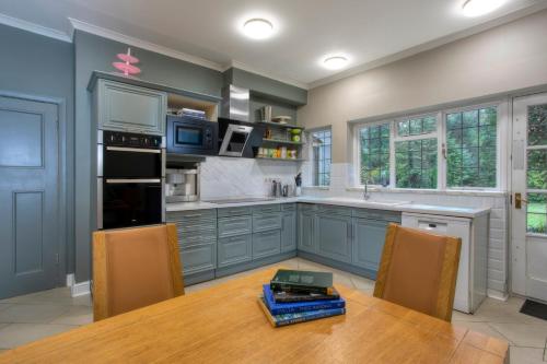 沃金的住宿－Coach house，厨房配有蓝色橱柜和一张带椅子的木桌