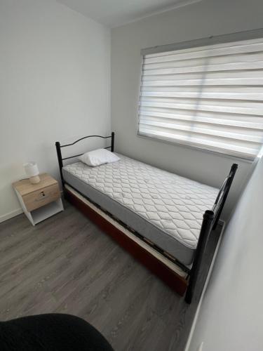 niewielka sypialnia z łóżkiem i oknem w obiekcie Casa Playa el Tabo en Condominio Estilo Mediterraneo w mieście El Tabo