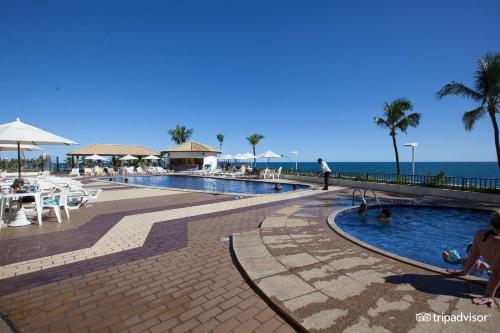 a swimming pool next to the ocean with people in it at Apartamento Aconchegante Beira-Mar Ondina in Salvador