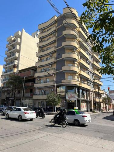 un gran edificio en una calle con coches y motocicletas en Departamento Romano’s en Santiago del Estero