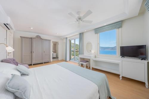 une chambre avec un lit, un bureau et une télévision dans l'établissement Villa Grande Kalkan, à Kaş