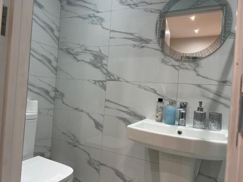 Baño blanco con lavabo y espejo en MIA Residence - Entire Studio apartment - City View - London - Next to Ealing Broadway Station, en Ealing