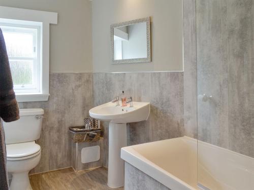 y baño con lavabo, aseo y espejo. en The Old School House Cottage, en Coupar Angus