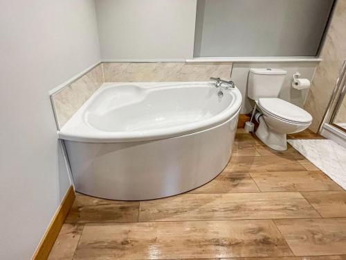 a bathroom with a white tub and a toilet at The Willows - Uk34000 in Child Okeford
