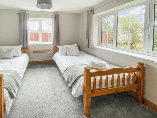 two beds in a room with two windows at The Willows - Uk34000 in Child Okeford