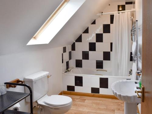a bathroom with a toilet and a sink and a tub at Kimberley Apartment in Alness