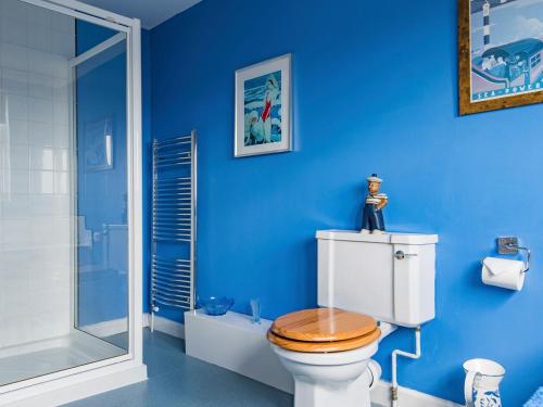 een badkamer met een toilet en een blauwe muur bij Helvetia in Dungeness