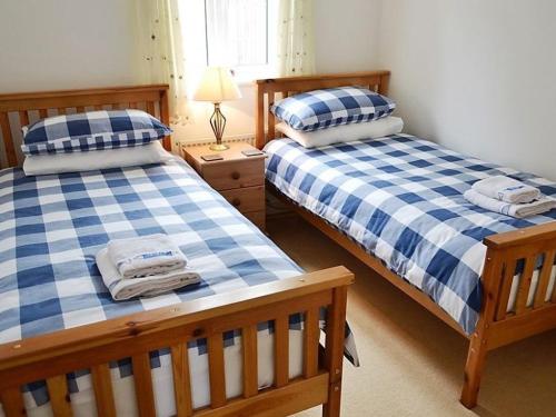 two beds in a bedroom with blue and white checks at Meadowside Apartment in Fowey