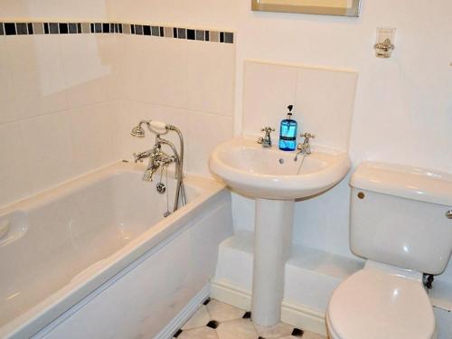 a bathroom with a sink and a toilet and a tub at Meadowside Apartment in Fowey
