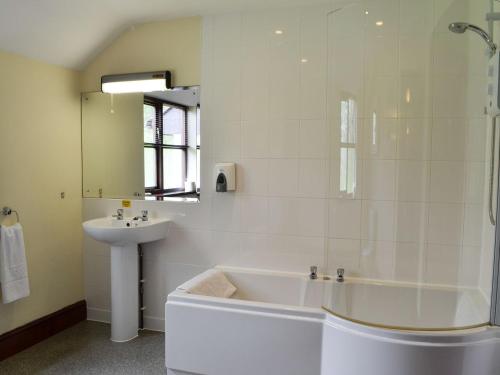 a white bathroom with a tub and a sink at Brynich Villa in Brecon