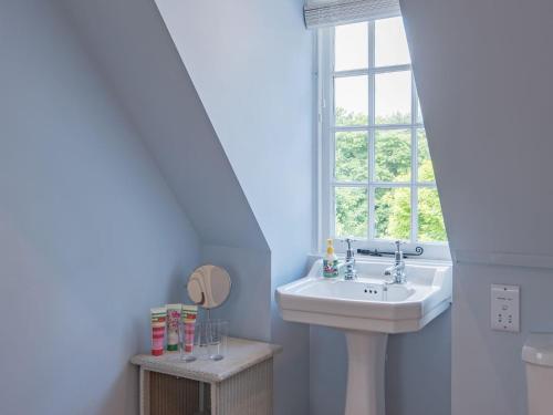 baño con lavabo y ventana en The Coach House Stables en Graveney
