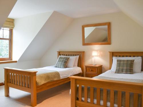 a bedroom with two beds and a mirror on the wall at Hawthorn House in Tomintoul