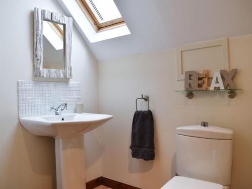 a bathroom with a sink and a mirror and a toilet at Hawthorn House in Tomintoul