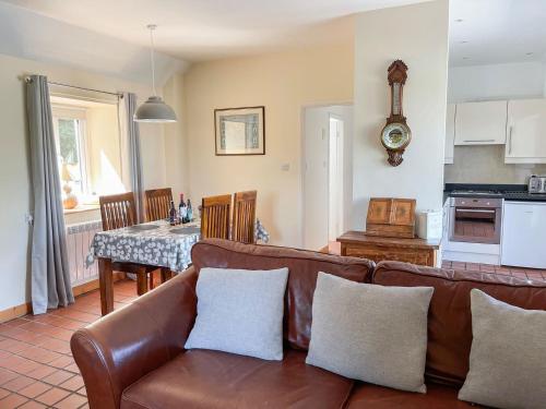 a living room with a couch and a kitchen with a table at The Smiddy in Glasserton