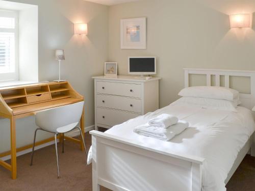 a bedroom with a bed and a desk with a computer at The Maltings in Bamburgh