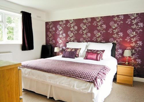 a bedroom with a large bed with purple wallpaper at Thalassa in Stoke Edith