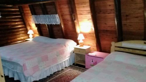 1 dormitorio con 2 camas en cabaña de madera en Cabañas De La Abuela en Mar de las Pampas
