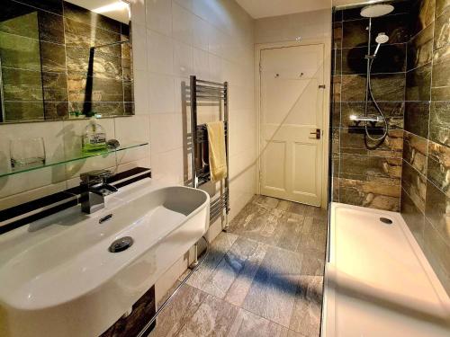 a bathroom with a tub and a sink and a shower at Lochside House in Stronachlachar