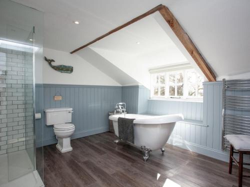 a bathroom with a white tub and a toilet at The Old Farmhouse in Chardstock