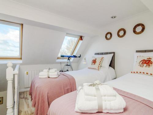 two beds in a room with white walls and a window at Church View Cottage in Goudhurst