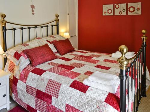 a bedroom with a bed with a red and white quilt at Beckside in Bellerby