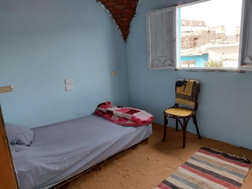 a bedroom with a bed and a chair and a window at ارجوندي جيست هاوس in Aswan