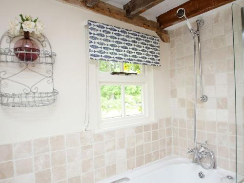 a bathroom with a bath tub and a window at Prospect Cottage in Wittersham