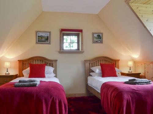 two beds in a attic room with red pillows at Loch Long View in Sallachy