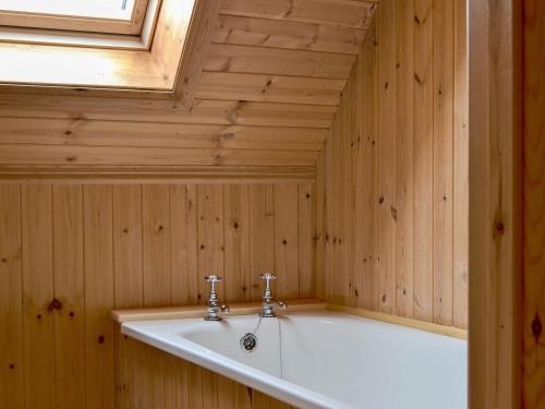 a bath tub in a wooden room with a window at Loch Long View in Sallachy