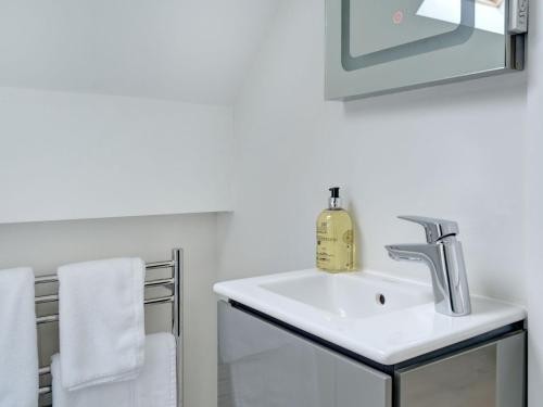 La salle de bains est pourvue d'un lavabo, d'un miroir et de serviettes. dans l'établissement Swallows Nest, à Bibury