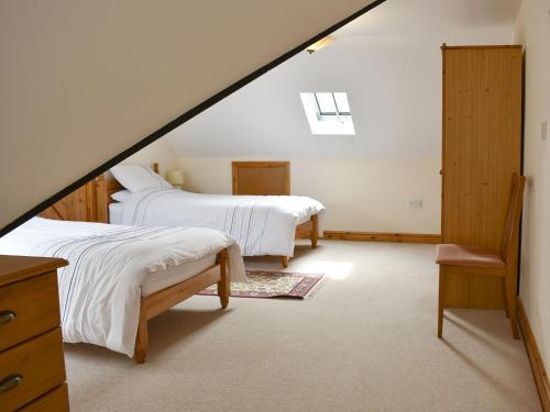 un dormitorio en el ático con 2 camas y una escalera en 2 Sawmill Cottages, en Puncknowle