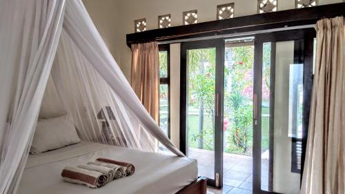 een slaapkamer met een hemelbed en handdoeken bij Salili Bungalow in Gili Air