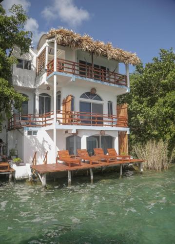 a house on a pier with chairs in the water at Seven Blue House Village & Lodge in Bacalar