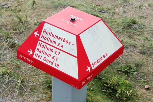 a red and white sign on a pole in the grass at TIME-OUT met ZONNIG TERRAS, eigen KEUKEN, Dichtbij Dorp, Duinen, Strand en Vuurtoren , Incl verwarmd Hotel-ZWEMBAD in Hollum
