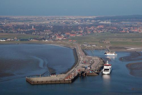 a boat is docked at a dock in the water at TIME-OUT met ZONNIG TERRAS, eigen KEUKEN, Dichtbij Dorp, Duinen, Strand en Vuurtoren , Incl verwarmd Hotel-ZWEMBAD in Hollum