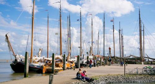 a group of people sitting next to a dock with sailboats at TIME-OUT met ZONNIG TERRAS, eigen KEUKEN, Dichtbij Dorp, Duinen, Strand en Vuurtoren , Incl verwarmd Hotel-ZWEMBAD in Hollum