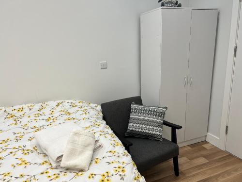 a bedroom with a bed and a chair at Park View Serviced Apartment - Next to Northolt Tube Station - Near Central London & Wembley in Northolt