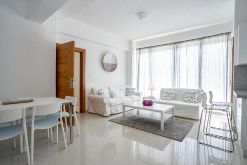 Sala de estar blanca con sofá y mesa en Brand New Harmony Apartment with Pool and Gym in La Julia, en Santo Domingo