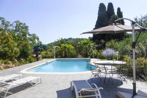 une piscine avec une table, des chaises et un parasol dans l'établissement Holiday Home in Gabian near Vineyards, à Gabian