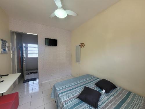 een slaapkamer met een bed en een plafondventilator bij Kitnet em frente à praia in São Vicente